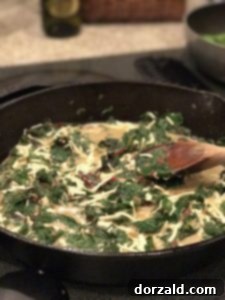 adding coconut milk creamer and dairy-free cheese to swiss chard mixture