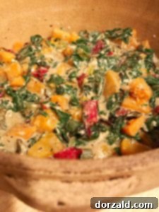 combining roasted vegetables and creamy chard mixture in a casserole dish