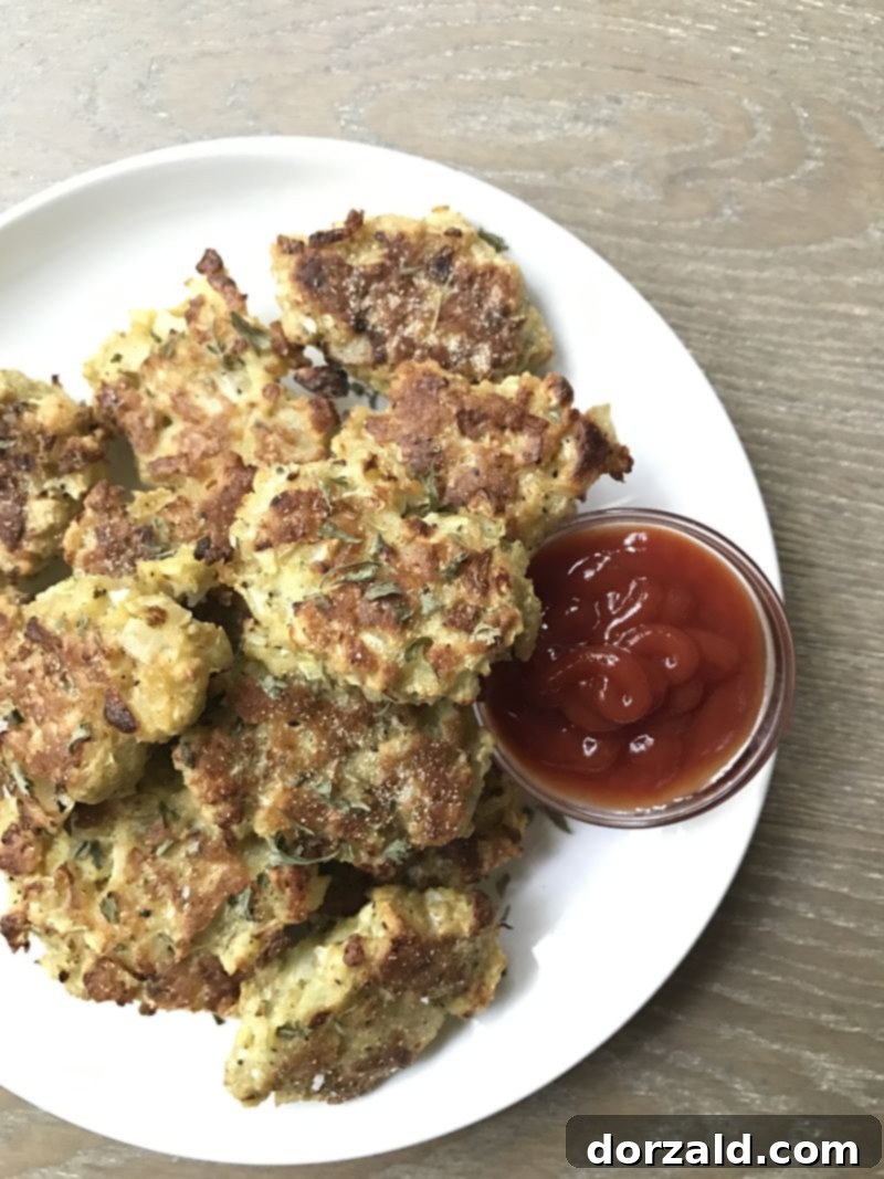 Golden brown gluten-free cauliflower tots on a baking sheet, ready to be served as a healthy snack or appetizer.