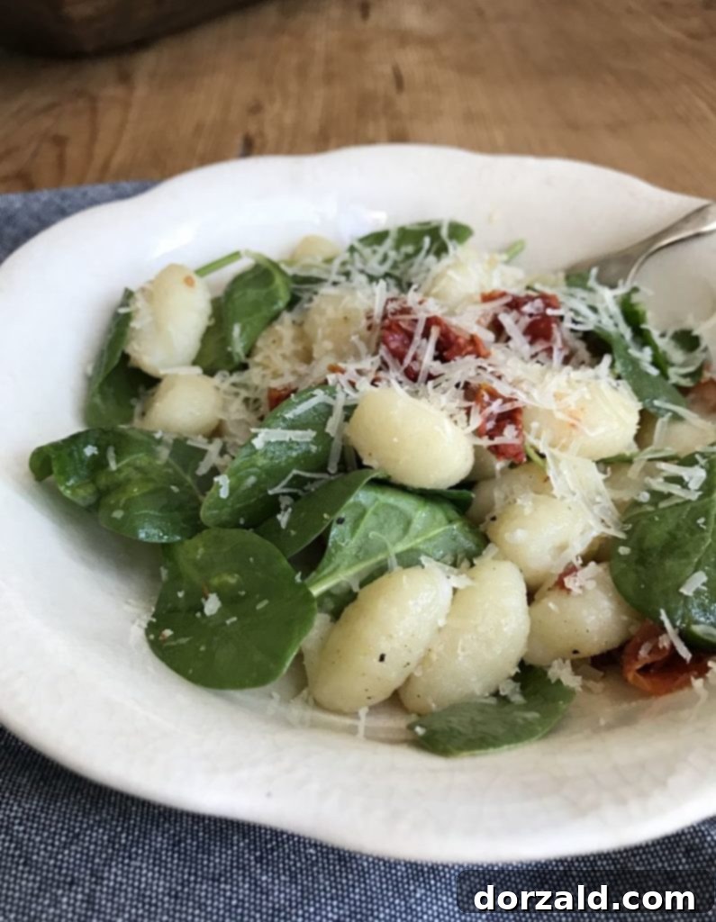 Simple Gnocchi with Bacon, Spinach and Sun-Dried Tomatoes 3 A close-up of Easy Gnocchi with Sun Dried Tomatoes Spinach and Bacon in a white bowl