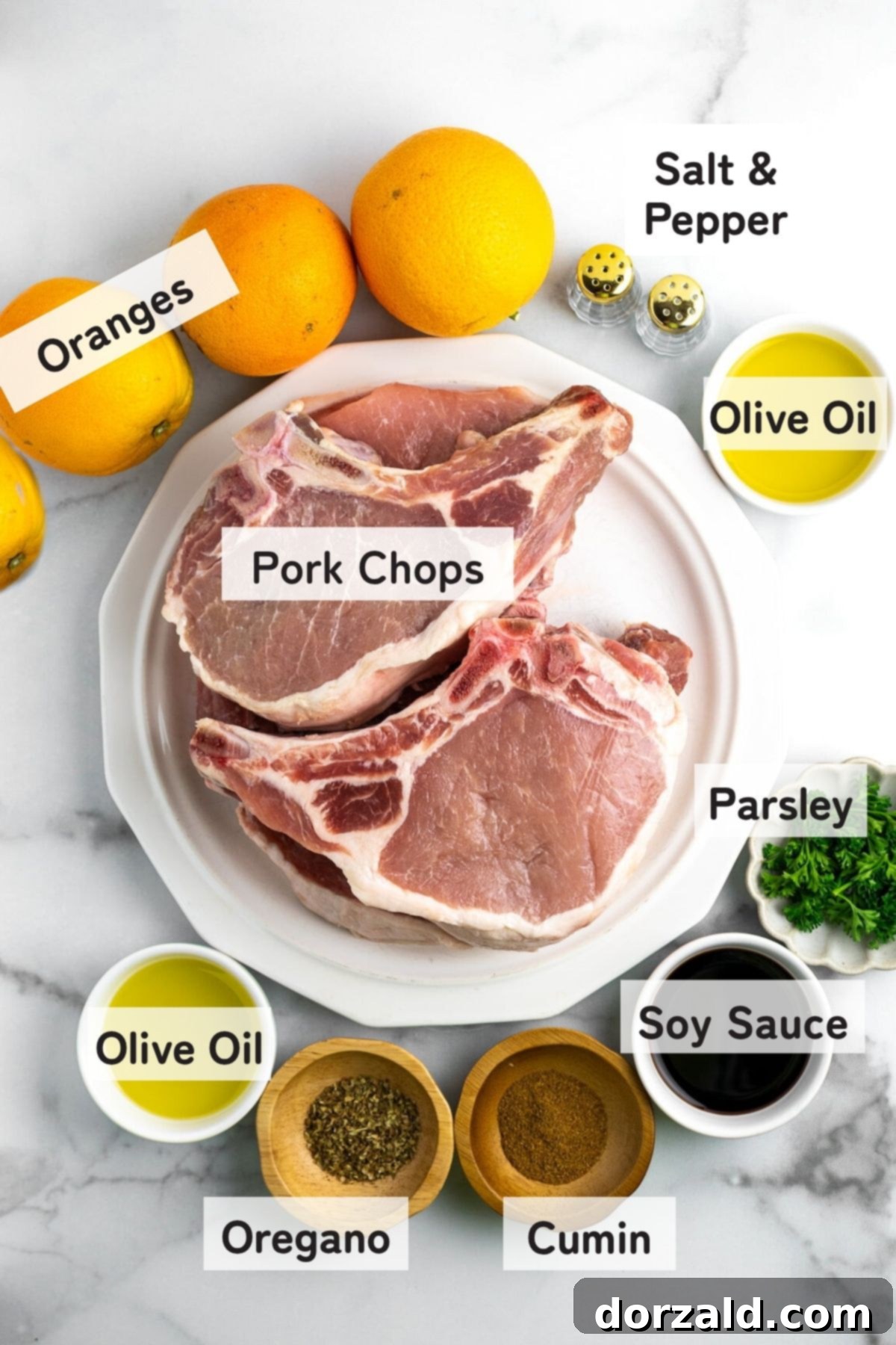 Variety of fresh ingredients for Mojo Pork Chops, including oranges, spices, and olive oil.