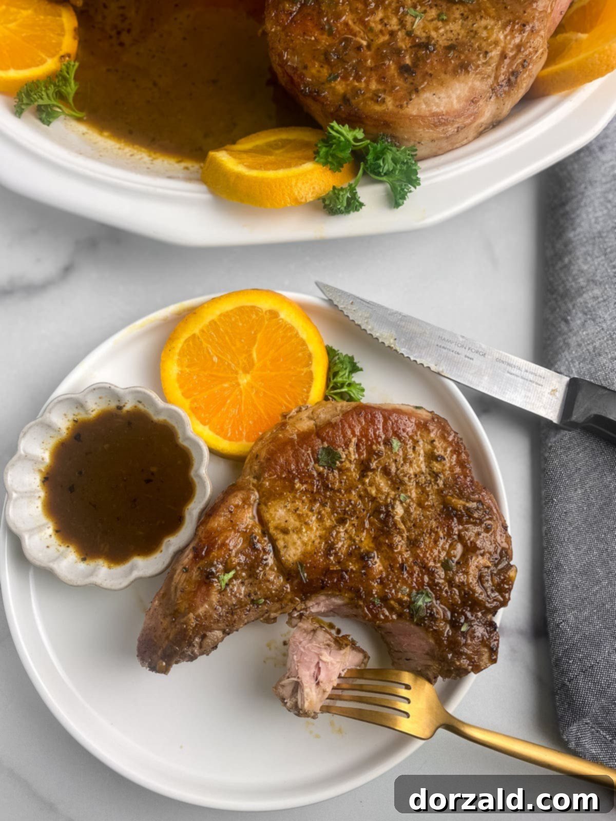 Plated pan-seared Mojo Pork Chops with sauce and garnish, ready to be served.