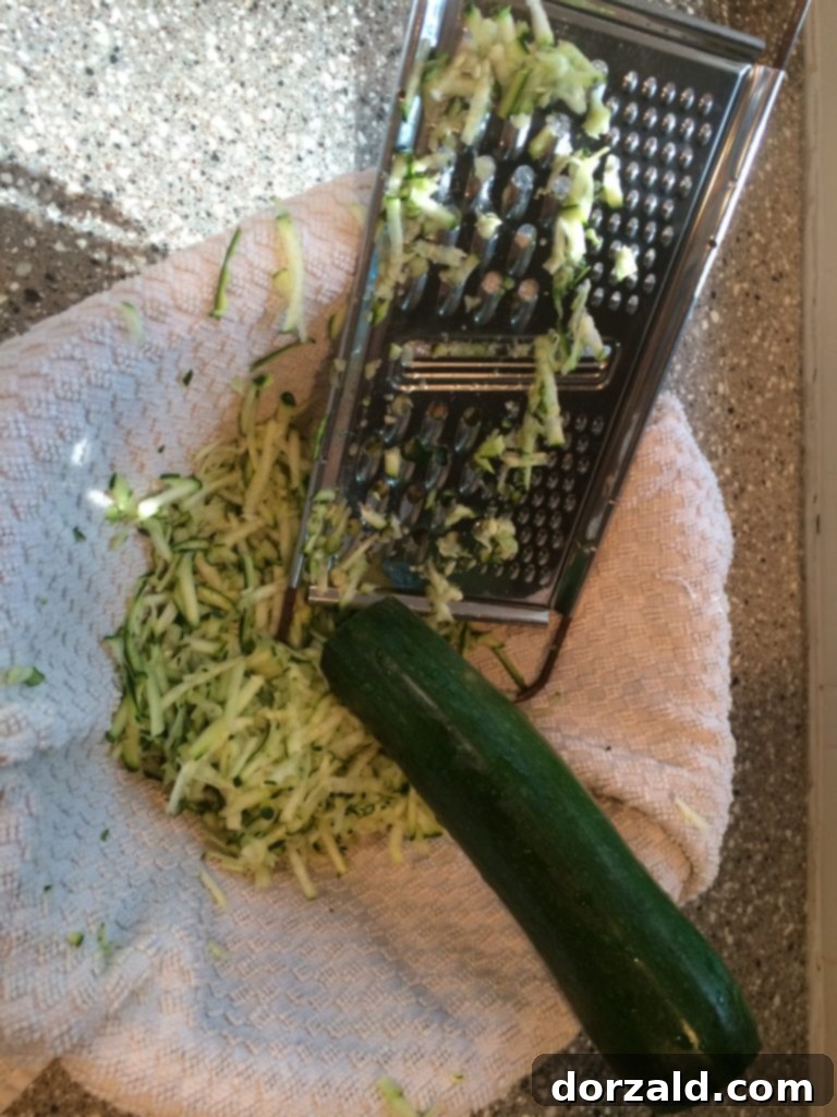 Crispy Zucchini Bites 3 Close-up of freshly grated zucchini in a bowl with a dish towel for squeezing