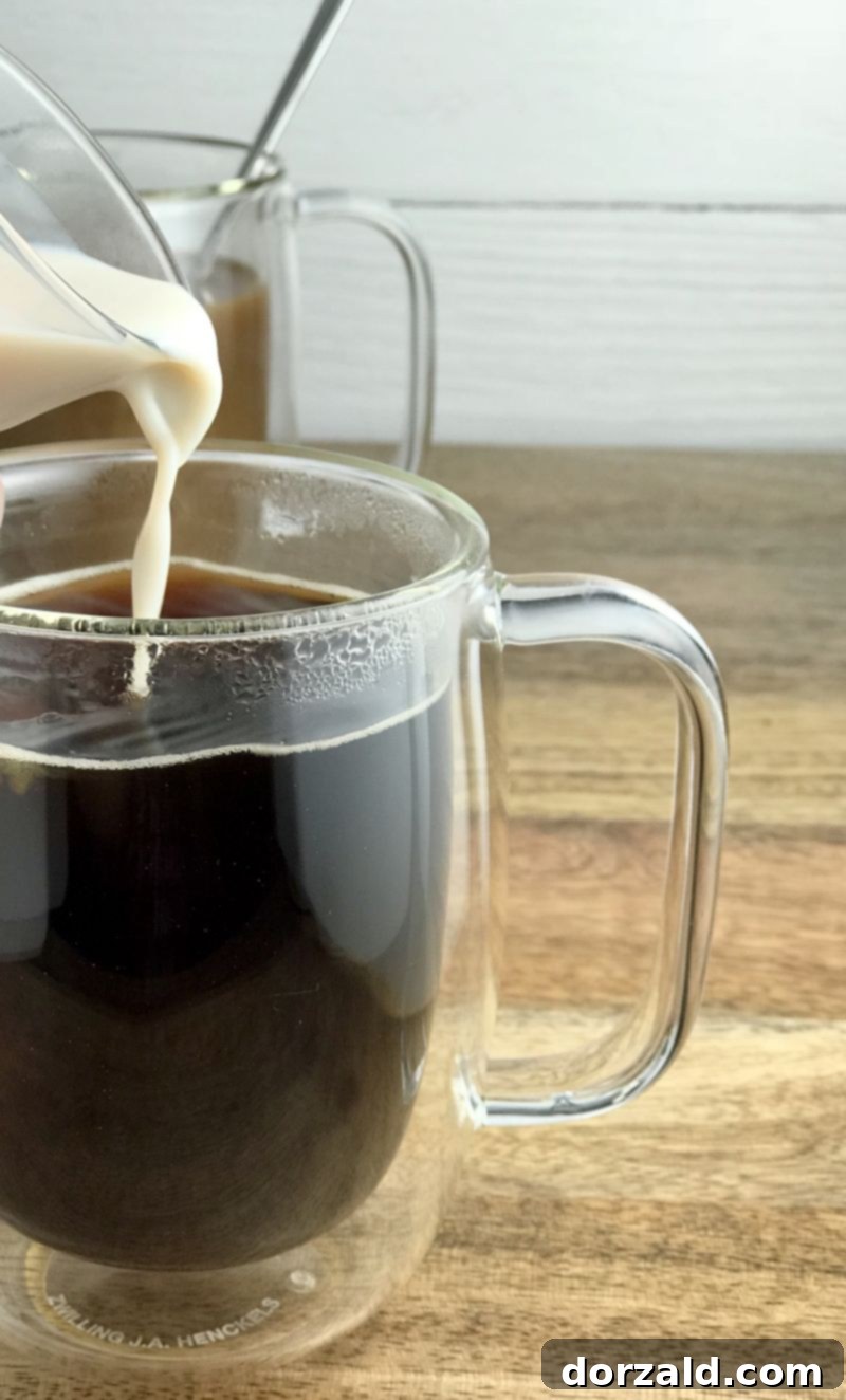 baileys almond milk liqueur bottle next to a mug of coffee and cinnamon stick