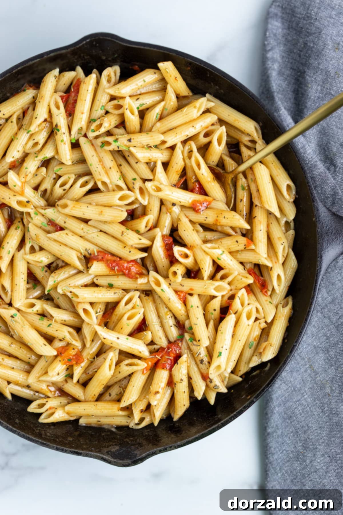 A bowl of creamy dairy-free tomato pasta with fresh basil garnish.