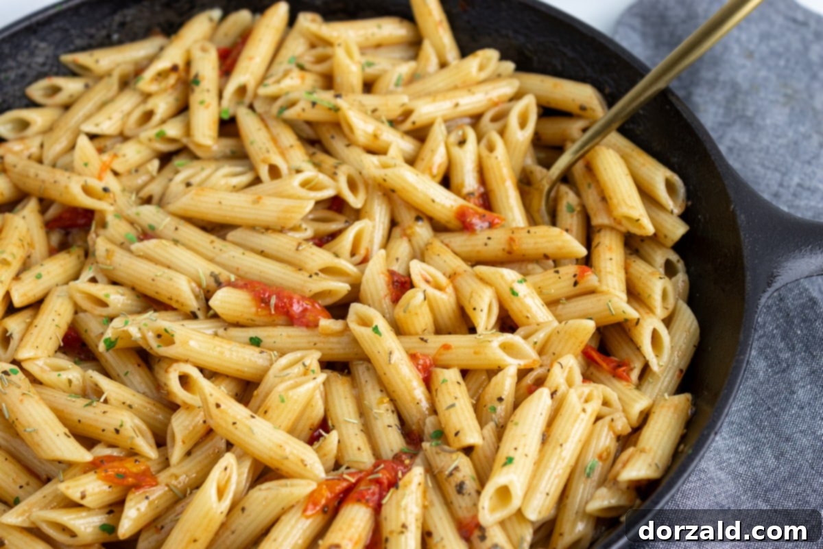 A large skillet filled with creamy dairy-free tomato pasta, ready to be served.