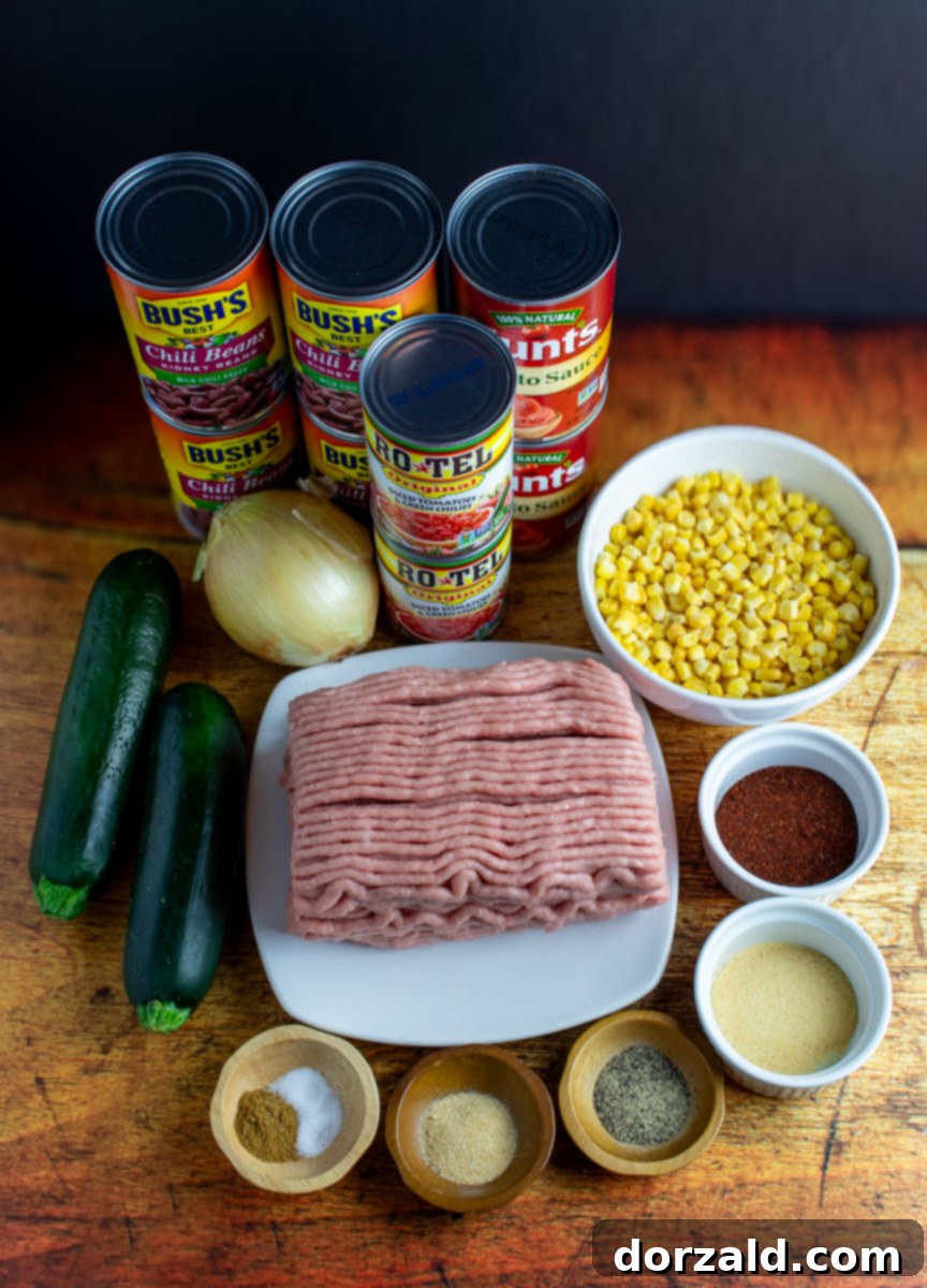 A selection of fresh ingredients including ground turkey, canned goods, zucchini, and spices laid out for making chili.