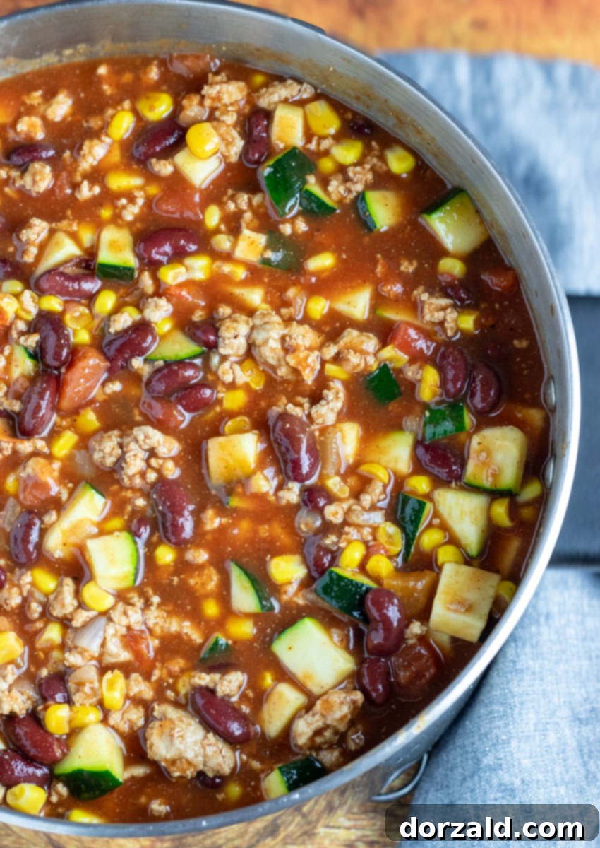 A large pot of simmering Vegetable Turkey Chili, rich with vegetables and beans, ready to be served.