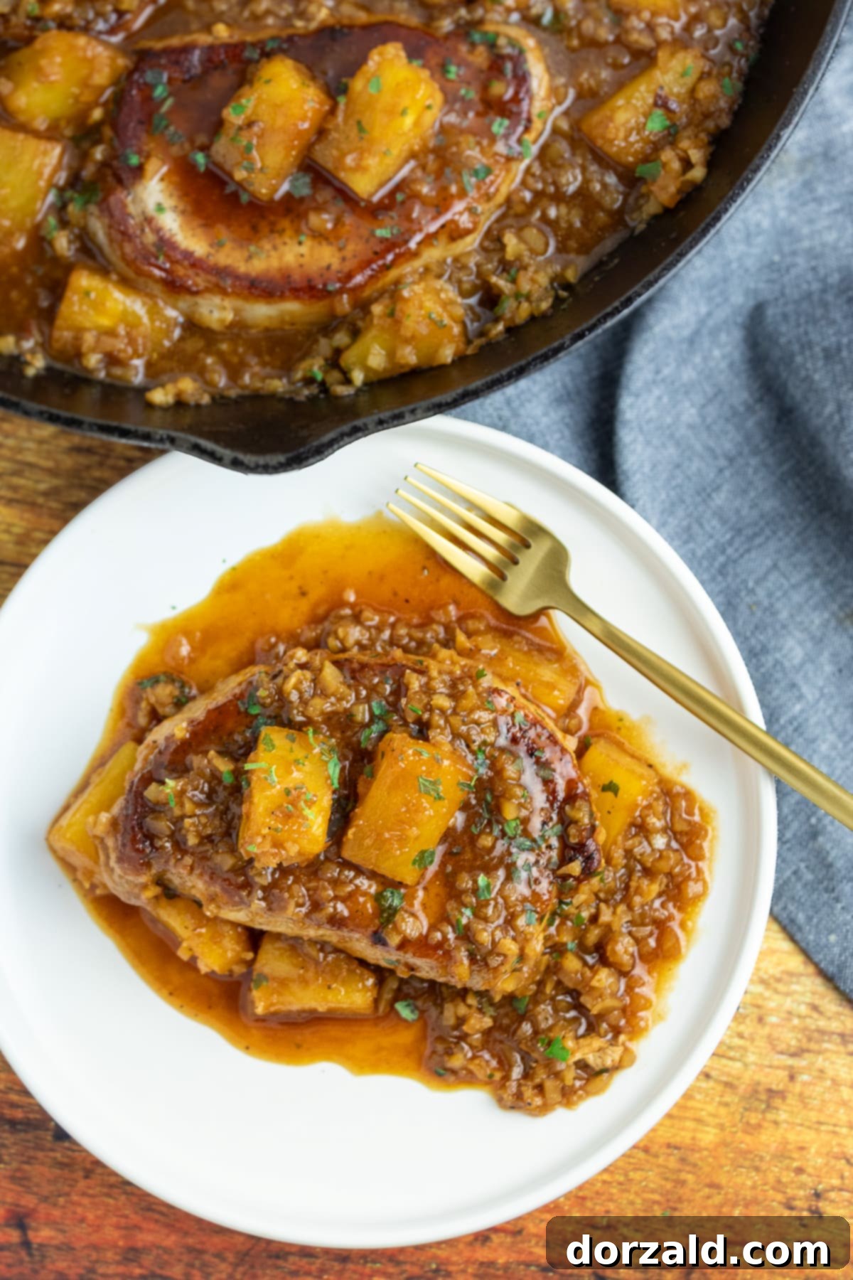 Plated brown sugar pineapple pork chops with riced cauliflower and fresh parsley garnish