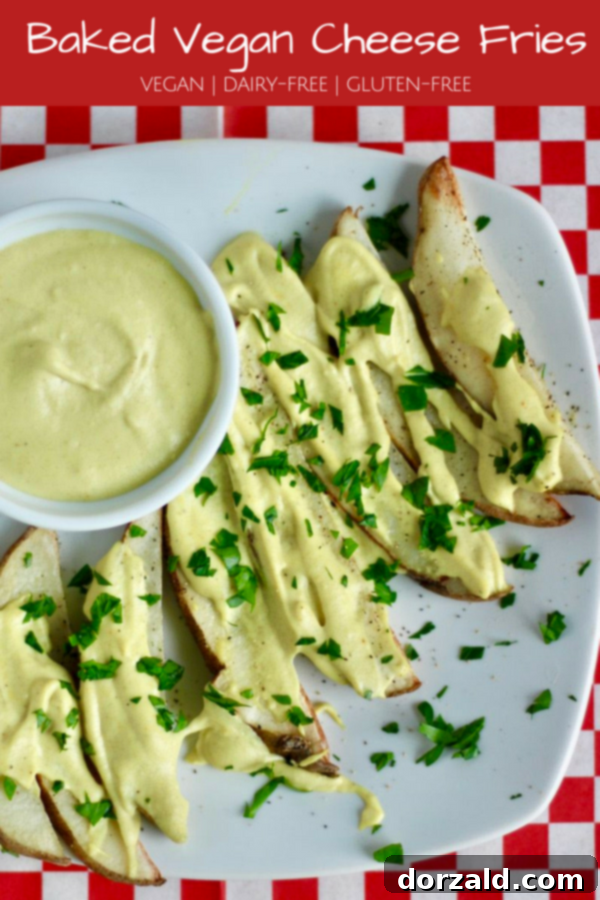 Delicious serving of Baked Vegan Cheese Fries with extra sauce on the side, garnished with fresh chives, ready to be enjoyed