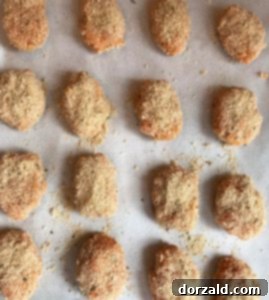 Formed sweet potato tots coated in breadcrumbs on a baking sheet