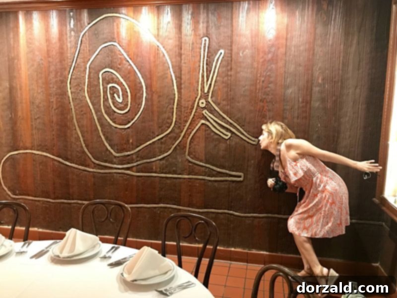 Kelly Kirkendoll embracing the whimsical charm of Antoine's Restaurant in New Orleans with a snail mural