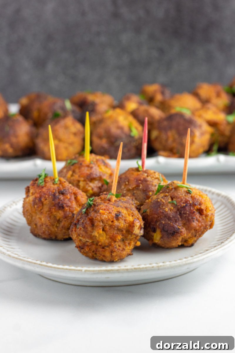 Spicy Turkey Chorizo Meatballs 3 Close-up of Turkey Chorizo Meatballs on a small plate with a large platter of meatballs in the background, ready for serving.