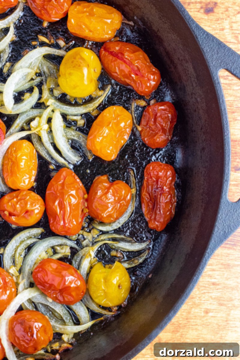 Oven Roasted Cherry Tomatoes in a skillet, close-up with visible garlic and onions