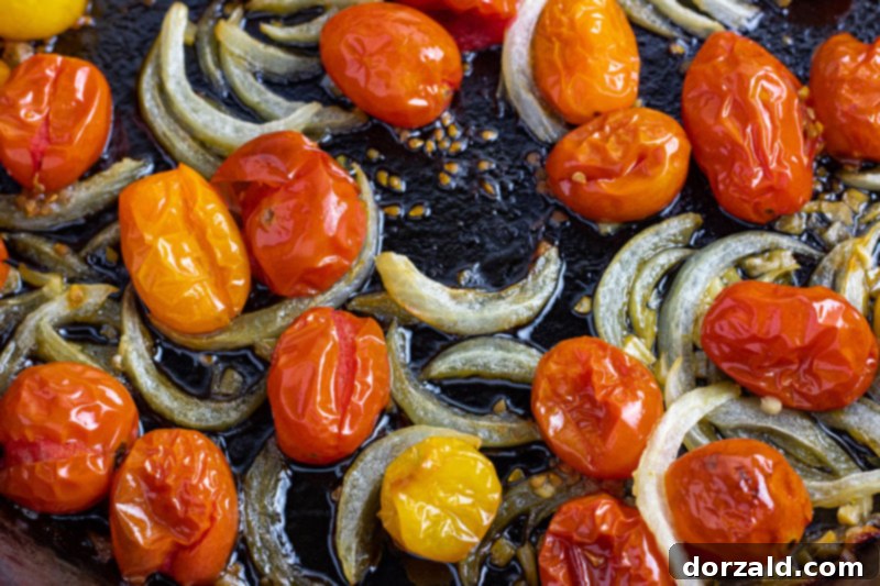 Close-up of easy oven roasted cherry tomatoes in a pan, blistered and juicy, showing caramelized edges
