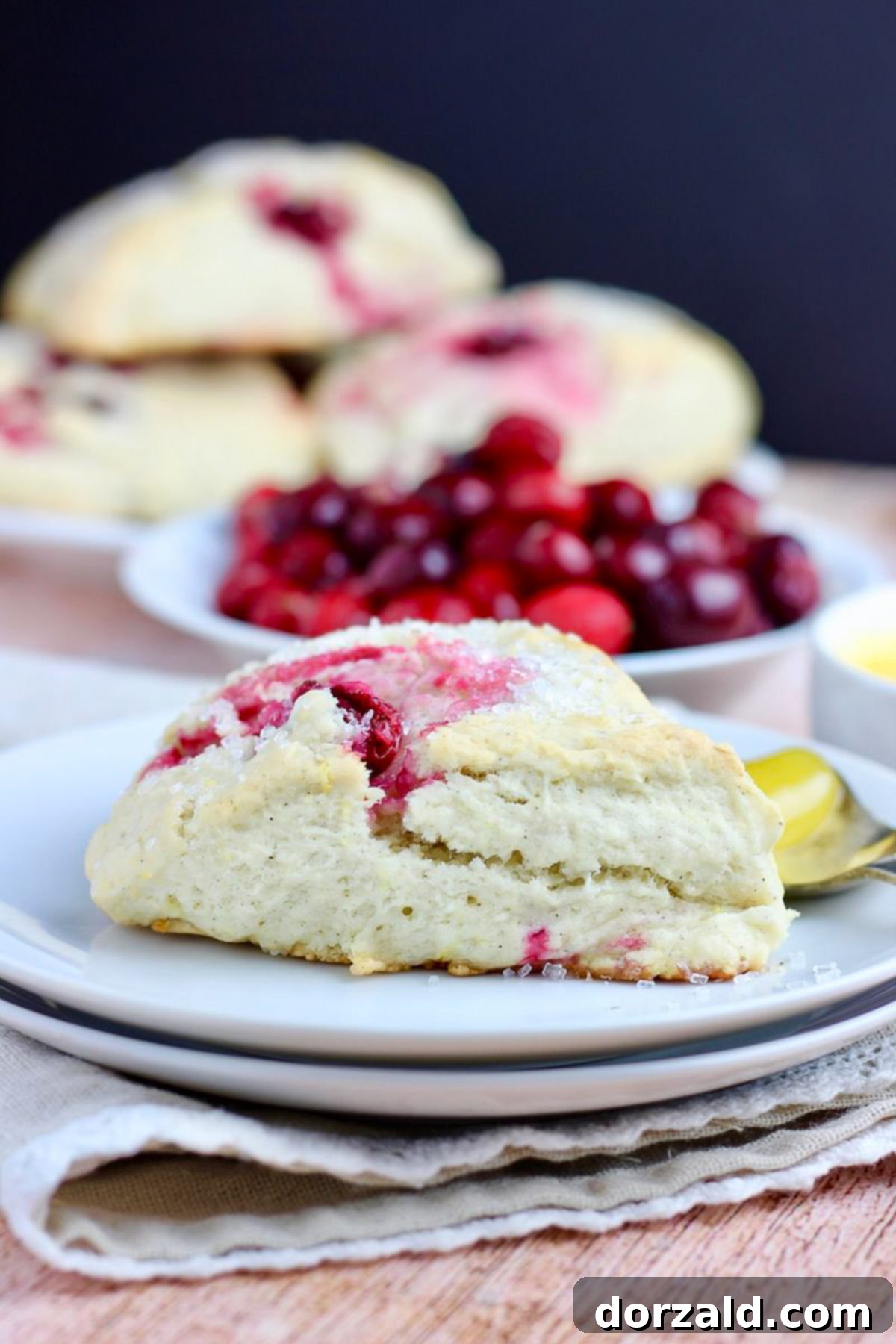 Plant Based Zesty Cranberry Scones 4 Close-up of fresh lemon zest being grated over cranberries and other ingredients in a bowl.
