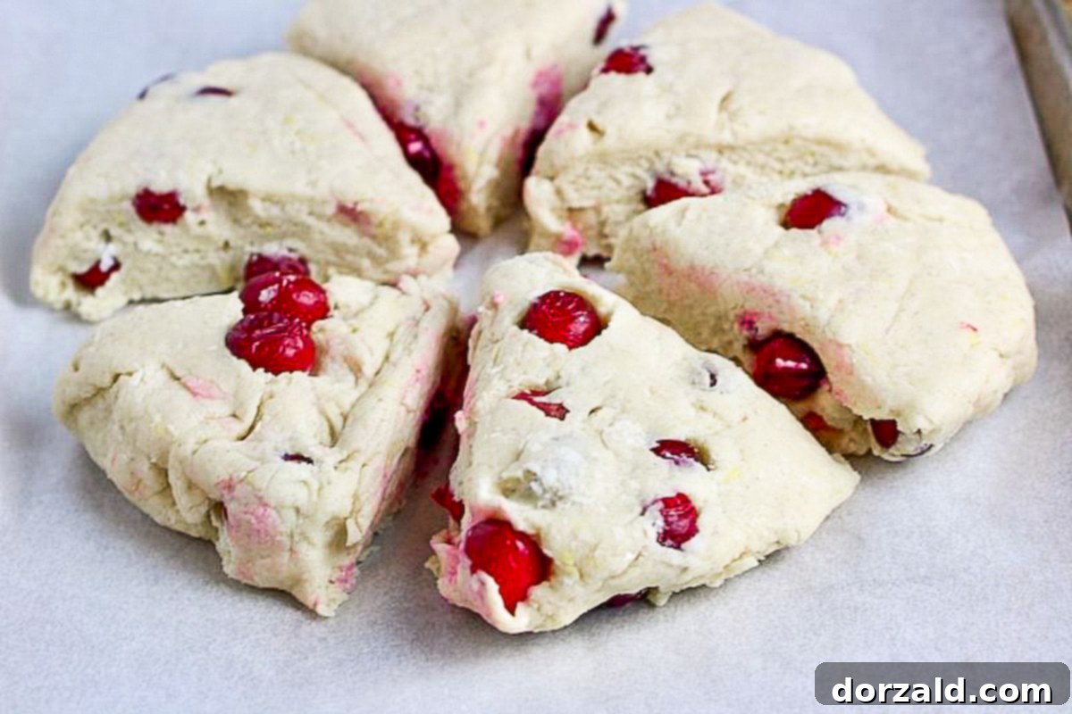 Raw scone dough cut into wedges on a parchment-lined baking sheet