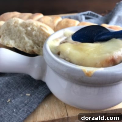 A bowl of homemade French Onion Soup, topped with melted cheese and a slice of toasted bread, ready to be served.