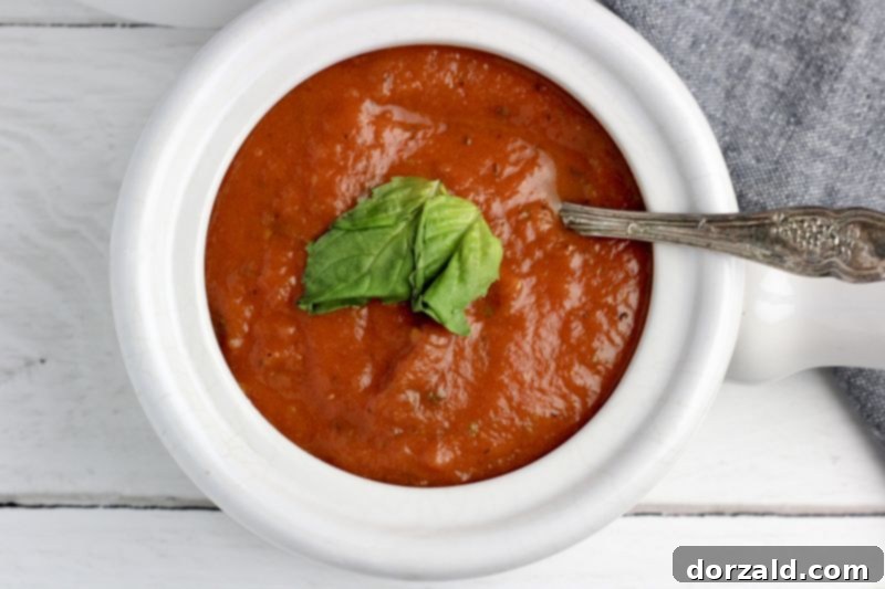 Close-up of fresh basil being added to a bowl of vegan Whole30 tomato basil soup