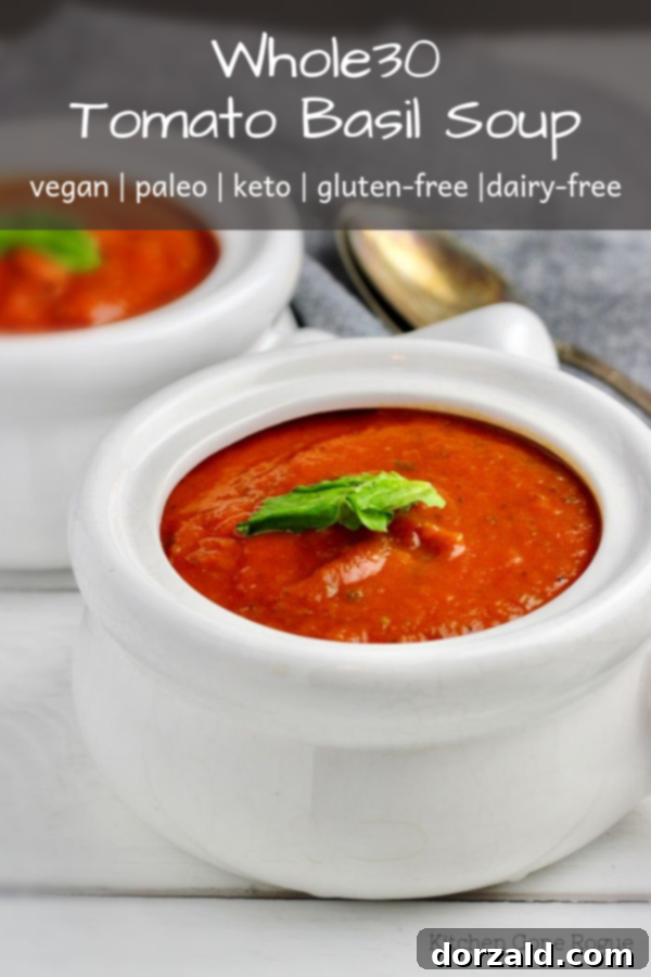 Overhead shot of a bowl of vegan Whole30 tomato basil soup with fresh basil and a spoon