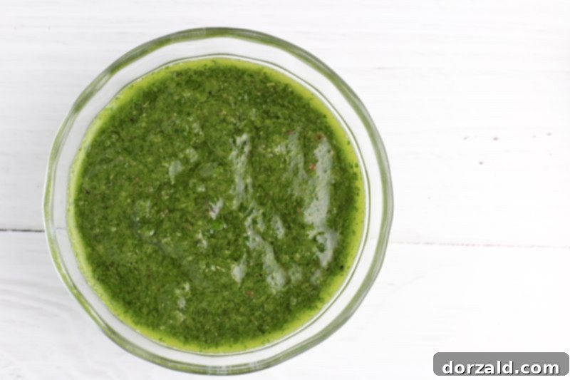 Paleo chimichurri sauce drizzled over a piece of steak and vegetables