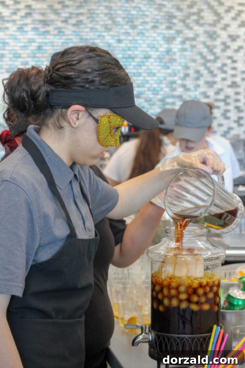 Student serving a smoking Mardi Gras-themed beverage