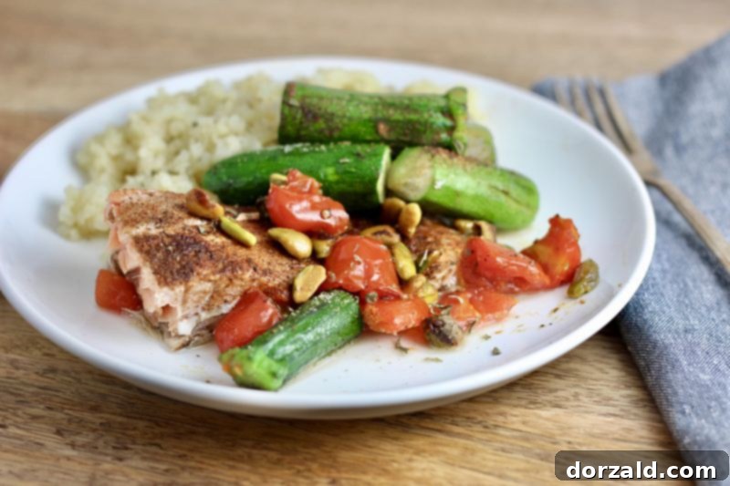raw salmon, pistachios, zucchini, and cherry tomatoes arranged on a white plate