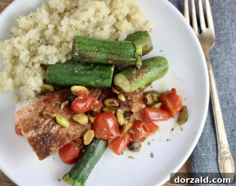 plated one pan pistachio salmon with roasted tomatoes and zucchini on a white plate