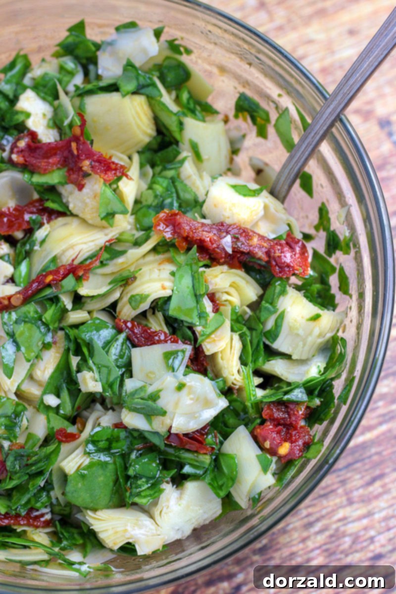 Vegetable mixture for bacon wrapped veggie stuffed chicken including spinach, garlic, artichokes, and sun-dried tomatoes