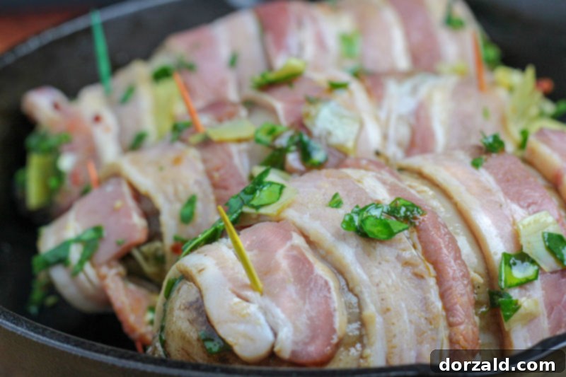Bacon Wrapped Veggie Stuffed Chicken ready for baking in a cast iron skillet