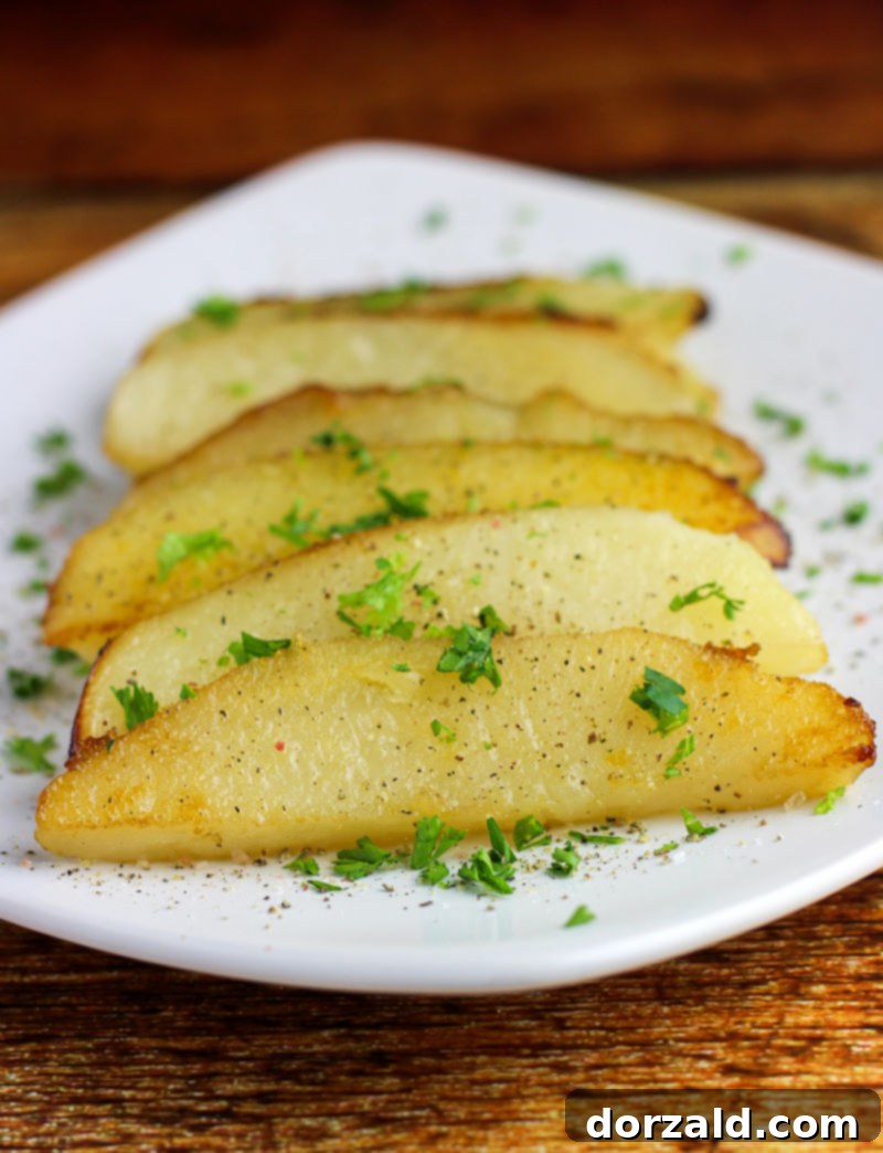 Close-up of roasted lemon potato wedges with fresh parsley on a white plate, ready to serve