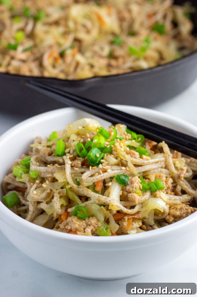 Crispy Egg Roll Soba Bowl 3 Egg Roll Soba Noodles in a white bowl with a black pan in the background, highlighting the ease of preparation.
