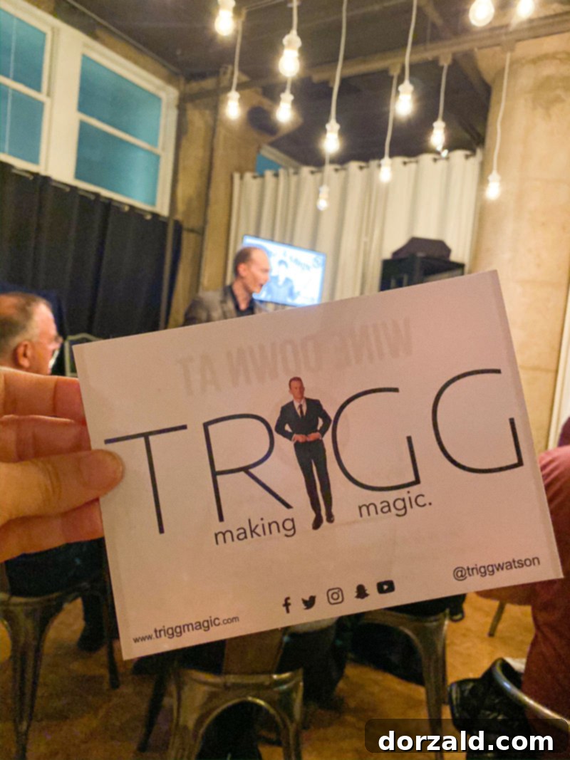 Trigg Watson engaging with the audience during his magic show, holding an object with an expression of surprise on an audience member's face.
