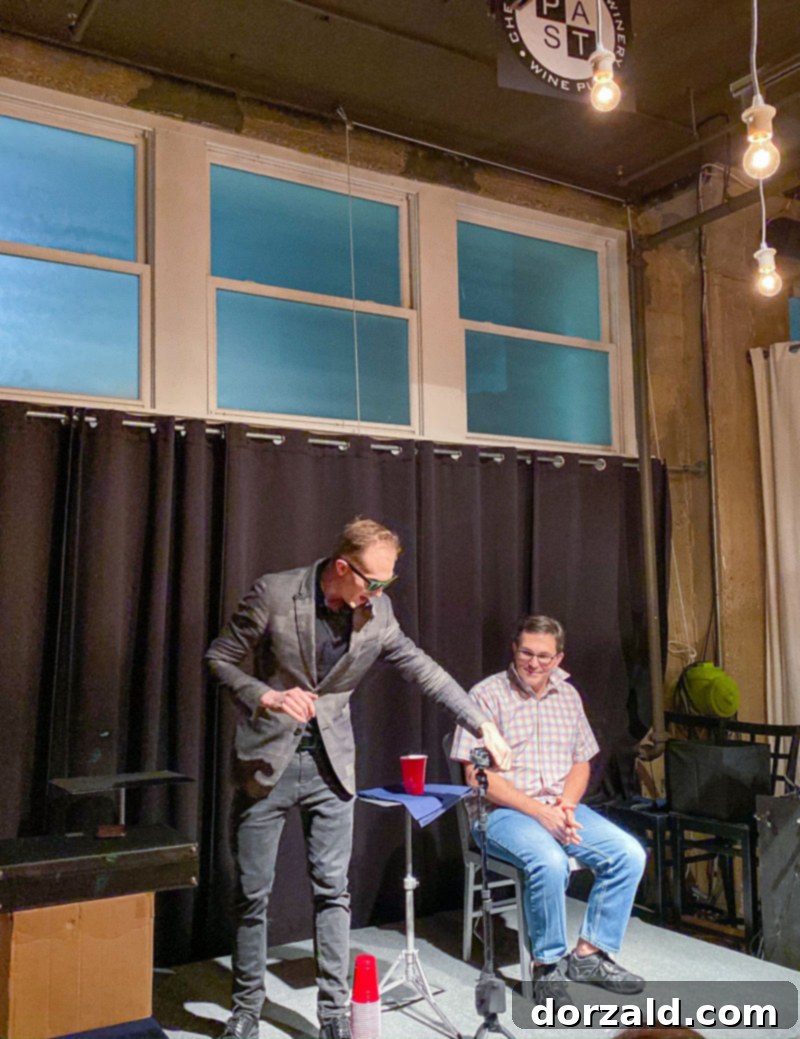 Trigg Watson performing a mind-bending magic trick, holding a card as he gazes intensely at the audience.