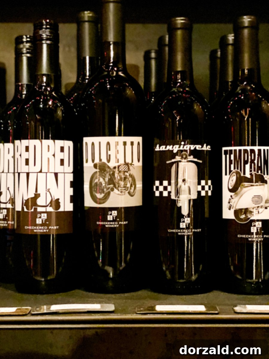A display of several bottles of Checkered Past Winery's Texas red wines, showcasing their labels and deep red hues.