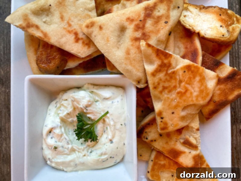 A close-up shot of a gourmet flatbread pizza topped with fresh vegetables, served with a glass of red wine.
