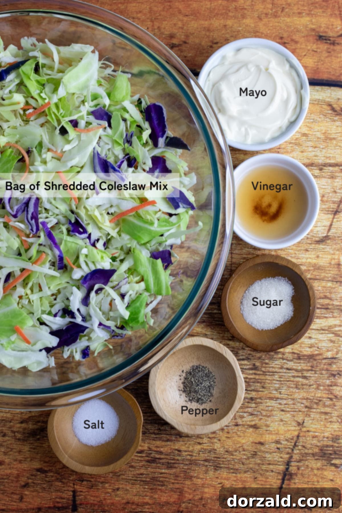 Collection of key ingredients for making easy 5-minute coleslaw: bagged coleslaw mix, mayonnaise, apple cider vinegar, sugar, salt, and pepper.