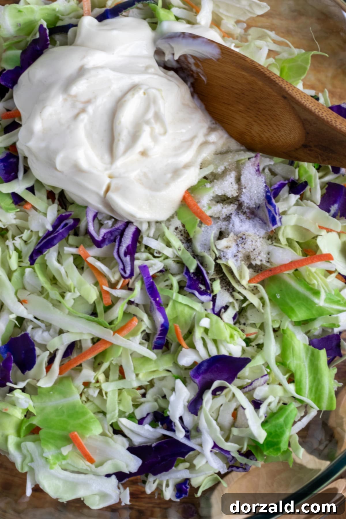 Shredded cabbage and carrots from a bagged coleslaw mix poured into a large white mixing bowl, ready for the dressing.
