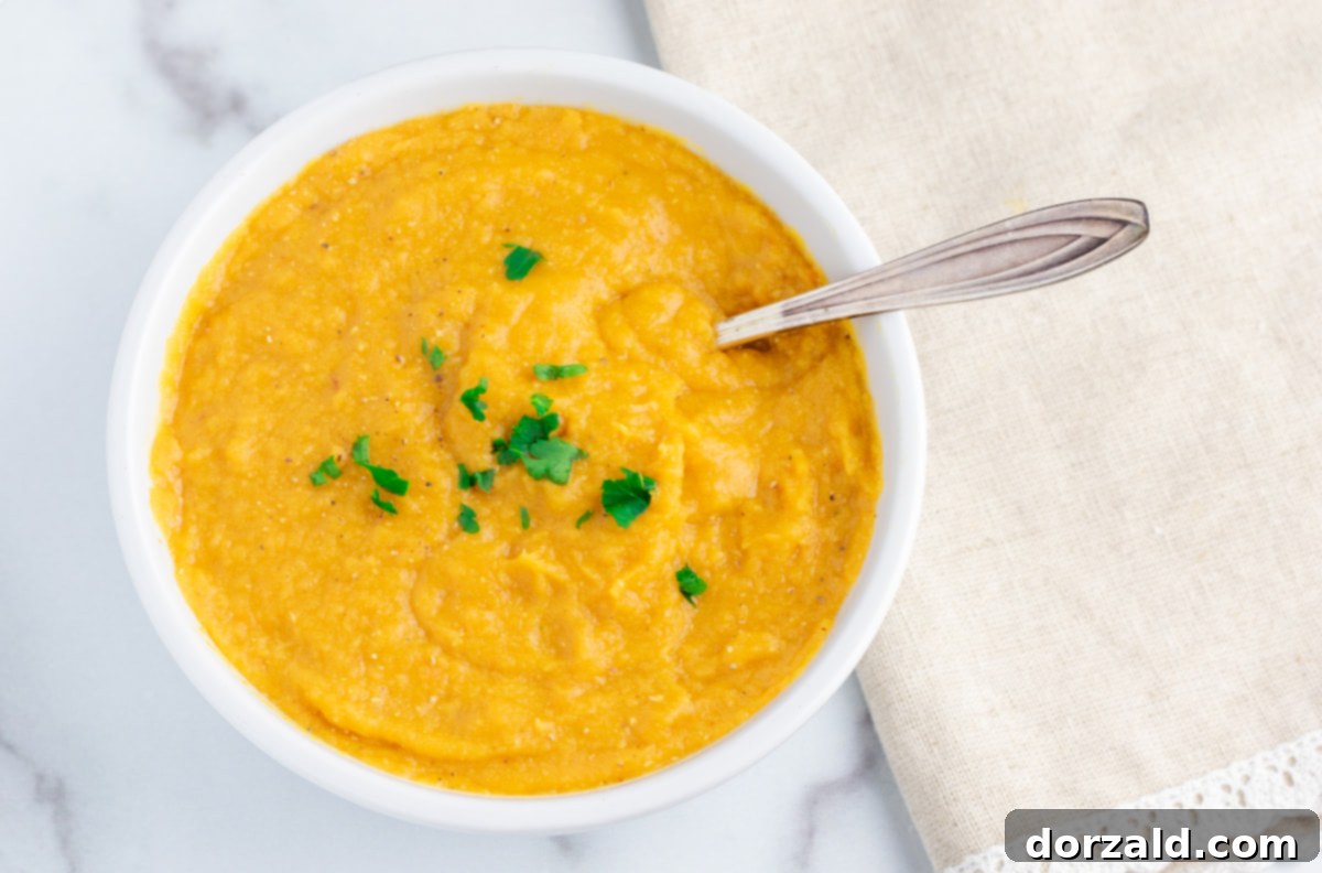A top-down view of a bowl of red lentil soup with garnishes and a spoon, ready to eat.
