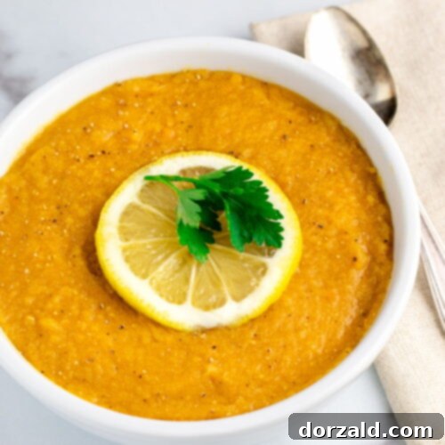 A close-up shot of the finished Red Lentil Soup with Lemon in a bowl, garnished with herbs.
