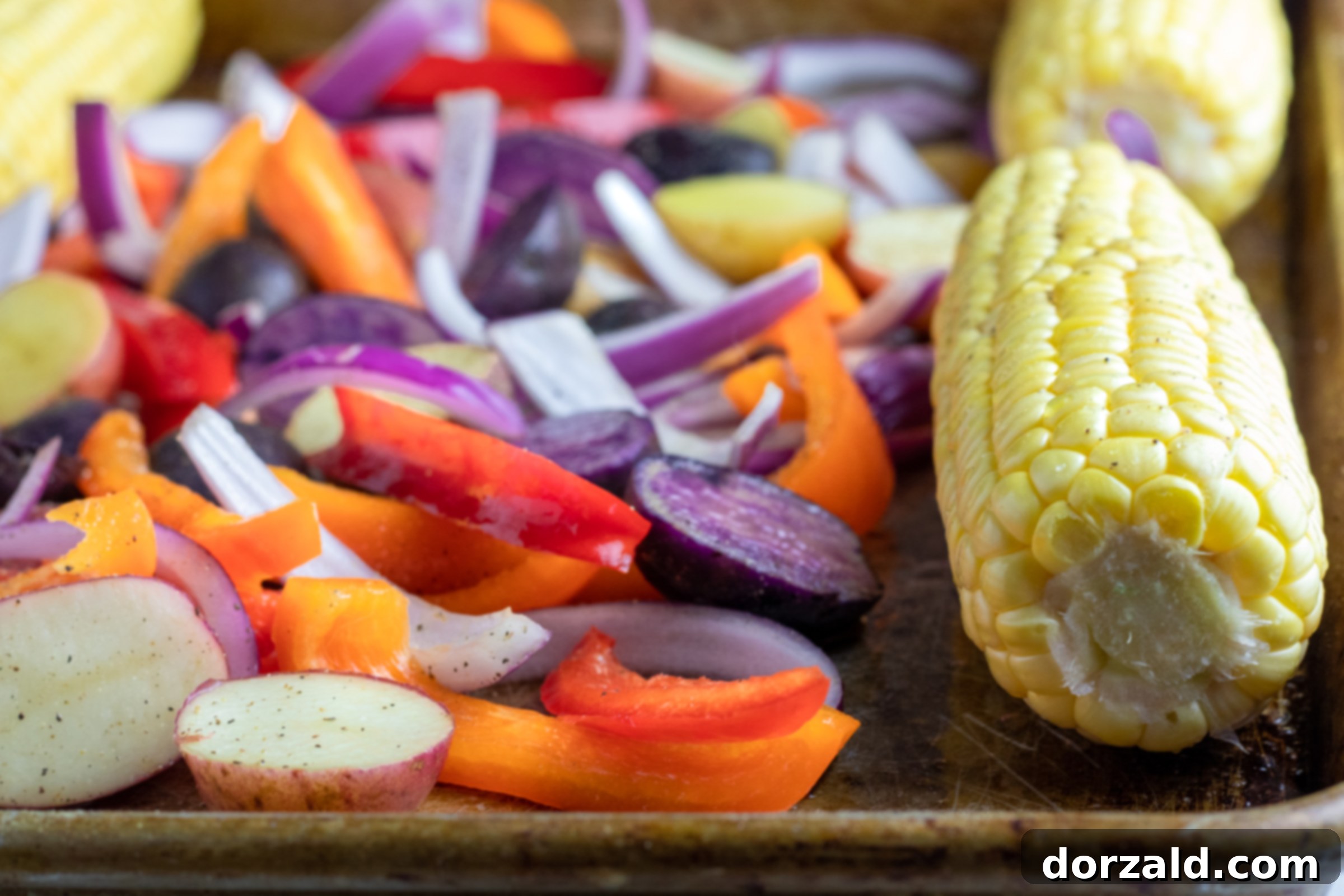 Easy One-Pan Roasted Salmon and Veggies 3 Sheet pan with colorful potatoes, peppers, and corn ready for roasting