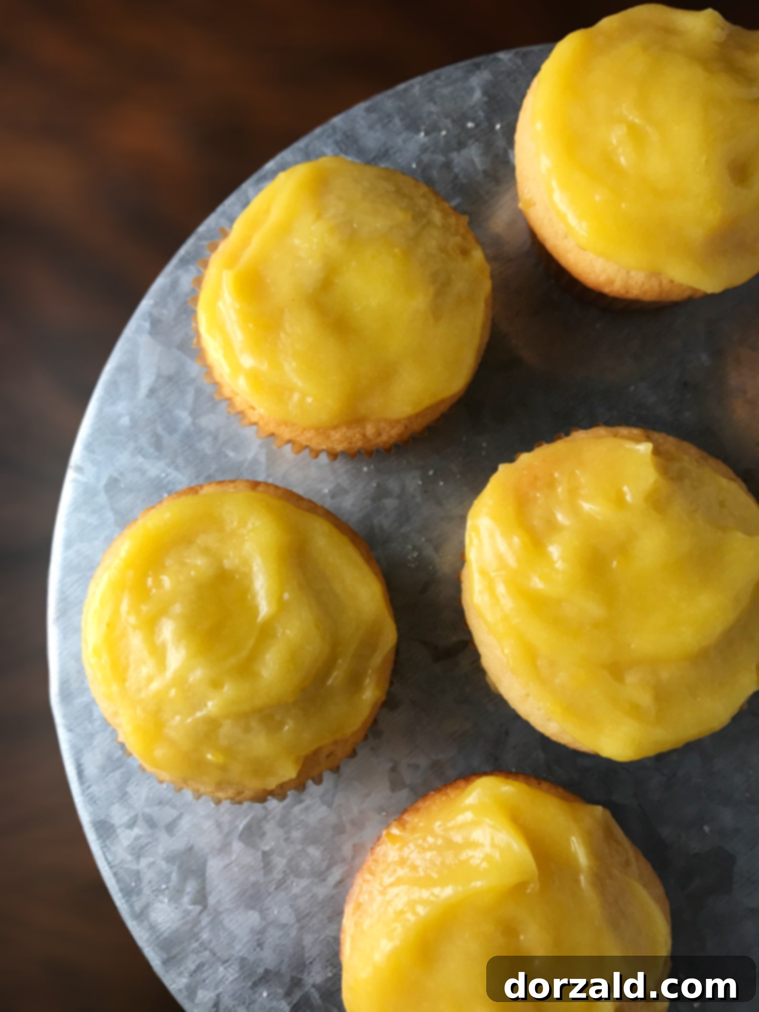 Freshly baked lemon cupcakes with a scoop of lemon curd on top