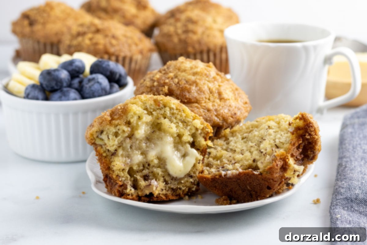 A basket of freshly baked dairy-free banana muffins, with one muffin pulled out to show its texture, surrounded by other breakfast items.