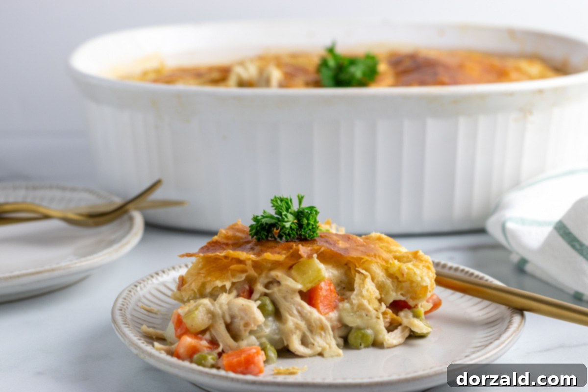 A perfectly baked dairy-free chicken pot pie, with a golden, flaky puff pastry crust, cooling on a wire rack. The crust is adorned with decorative cuts, hinting at the delicious filling within.