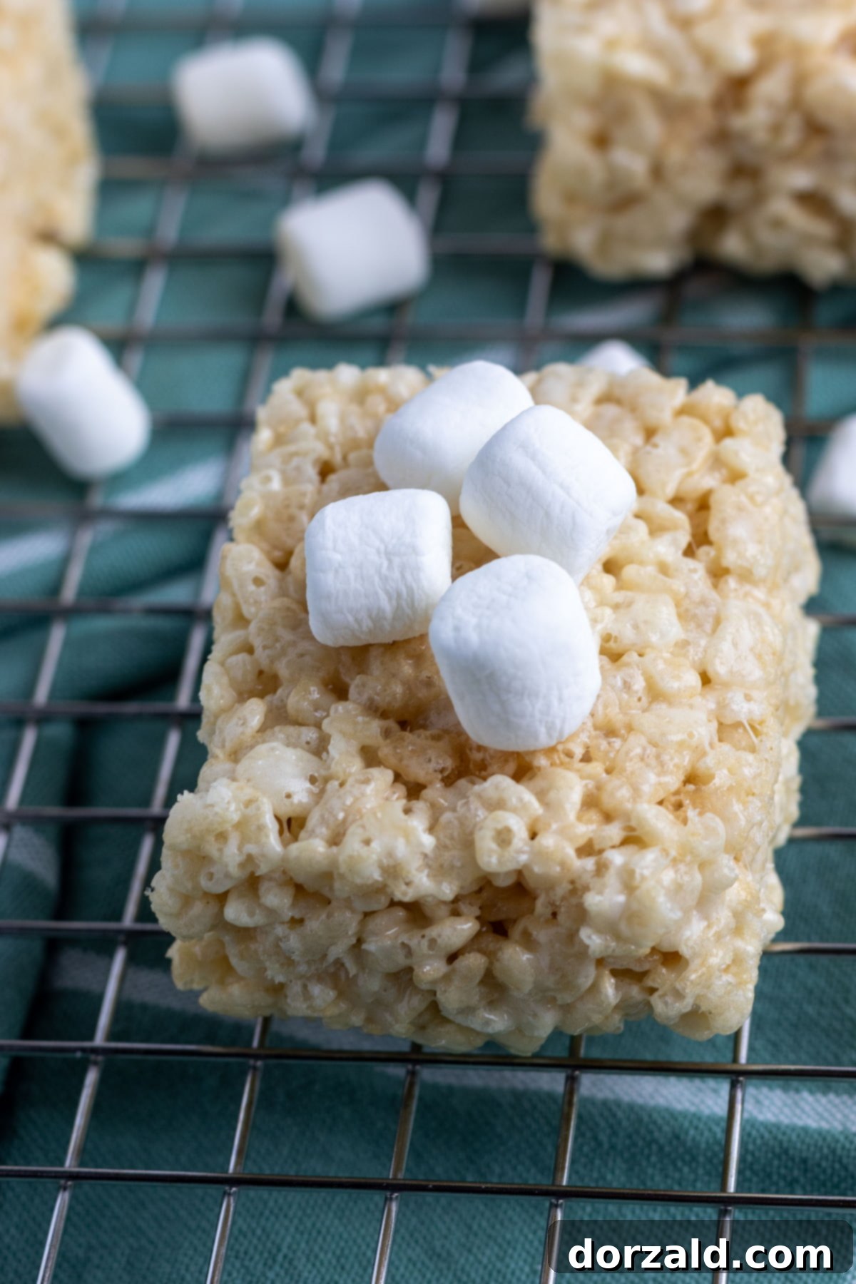 Close-up of a stack of golden brown dairy-free Rice Krispie treats, showing their soft, gooey texture and crispy cereal.