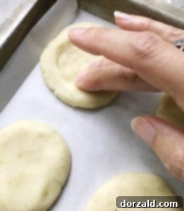 Cookie dough balls flattened on parchment paper