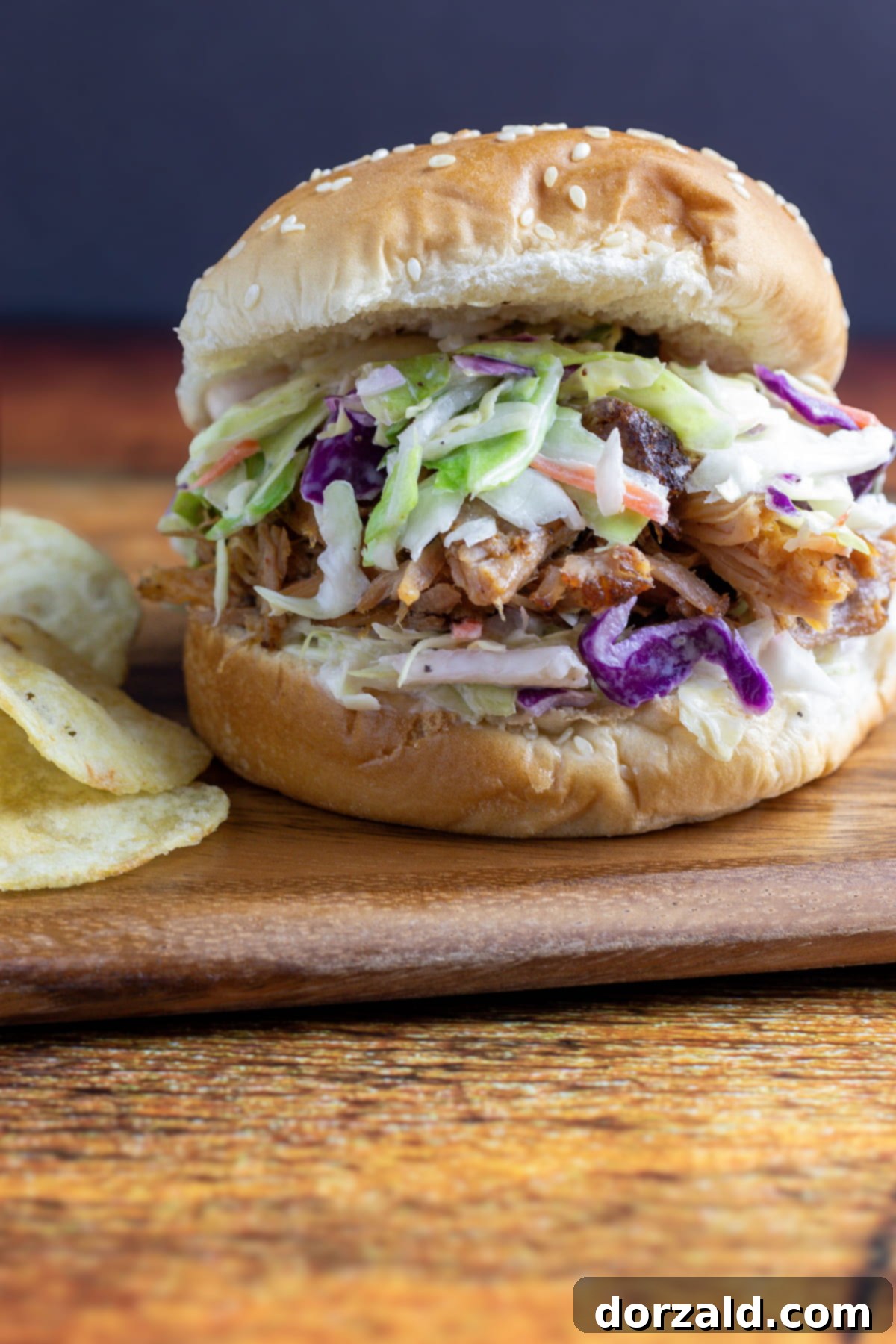 Smoked Pulled Pork and Creamy Slaw Sandwich 7 A finished Pulled Pork Coleslaw Sandwich, served on a plate with fresh ingredients in the background, ready for eating.
