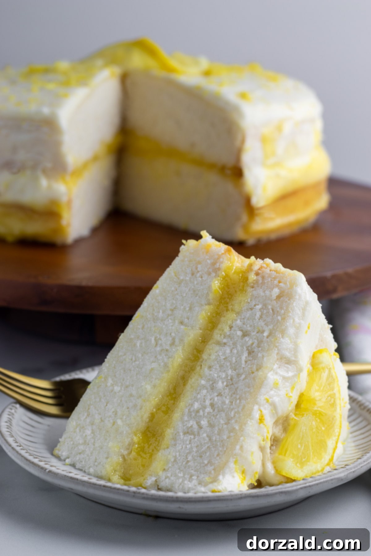 A beautifully decorated dairy-free lemon cake with lemon slices and zest on top, ready to be served.