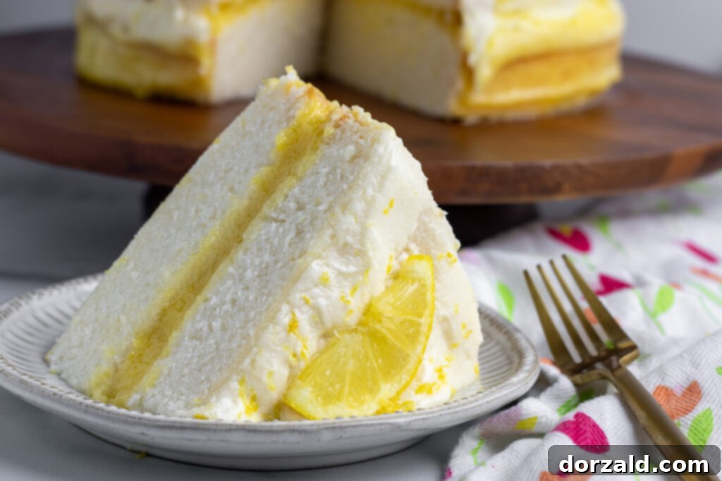 A top-down view of a beautifully frosted dairy-free lemon cake with a slice removed, showing the layers of cake and lemon curd.