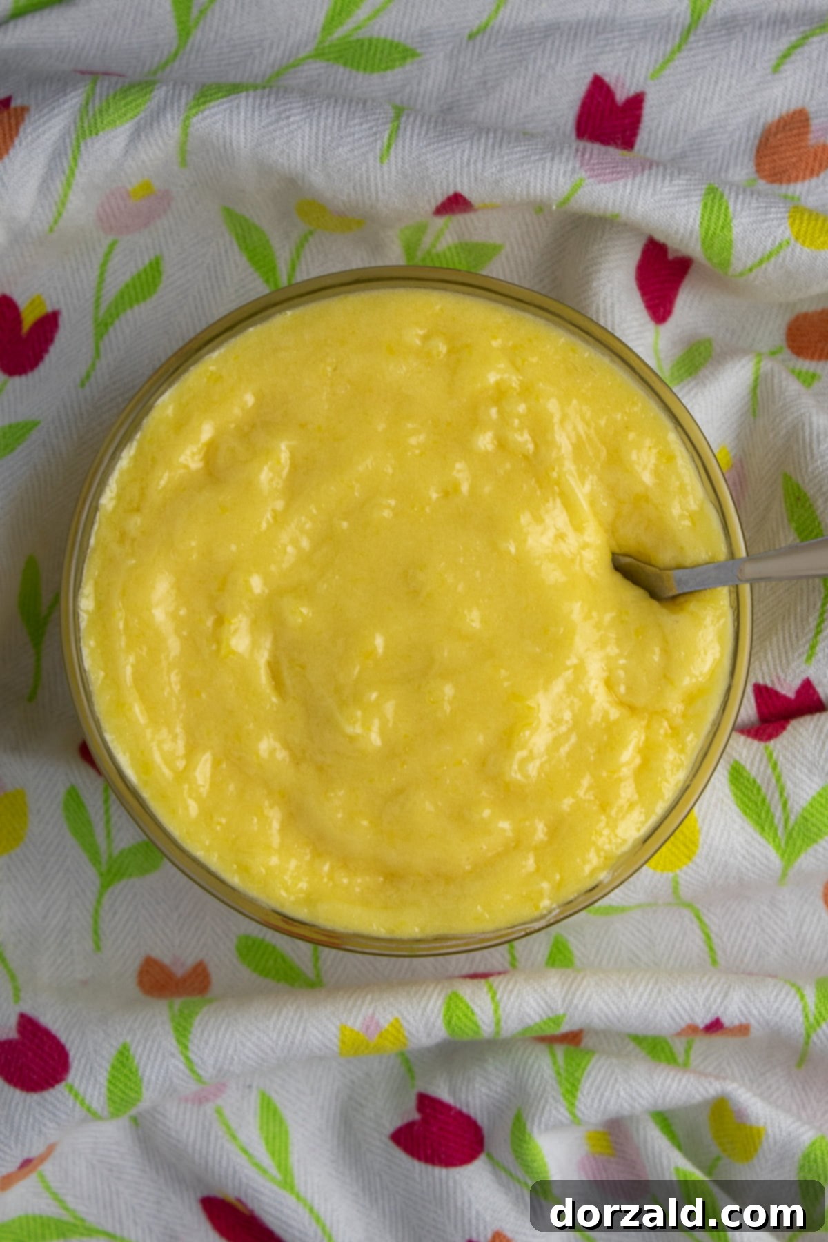 Homemade lemon curd being stirred in a saucepan.